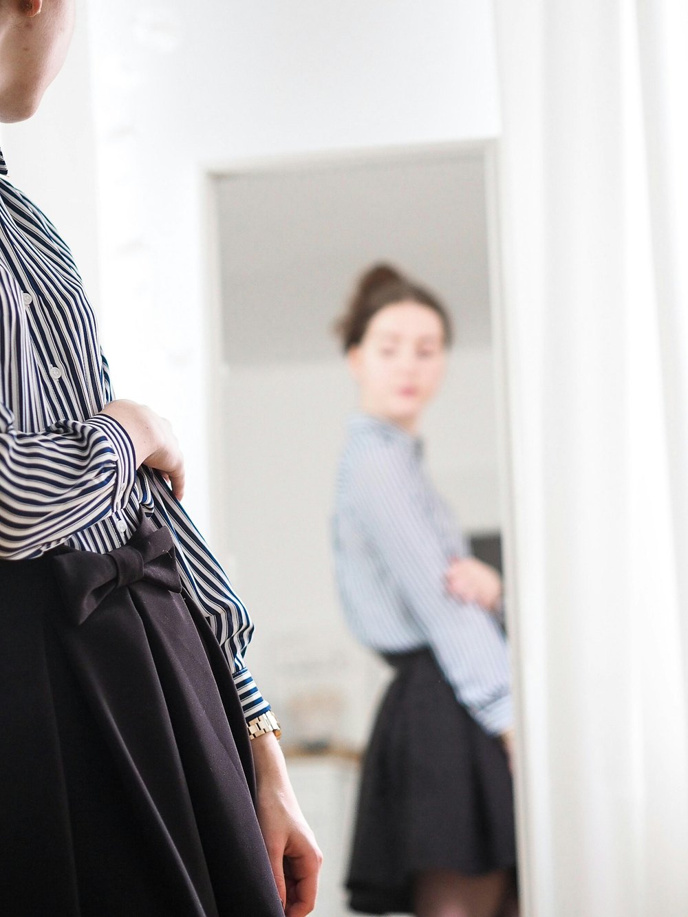 Checking a look in the mirror in a striped shirt