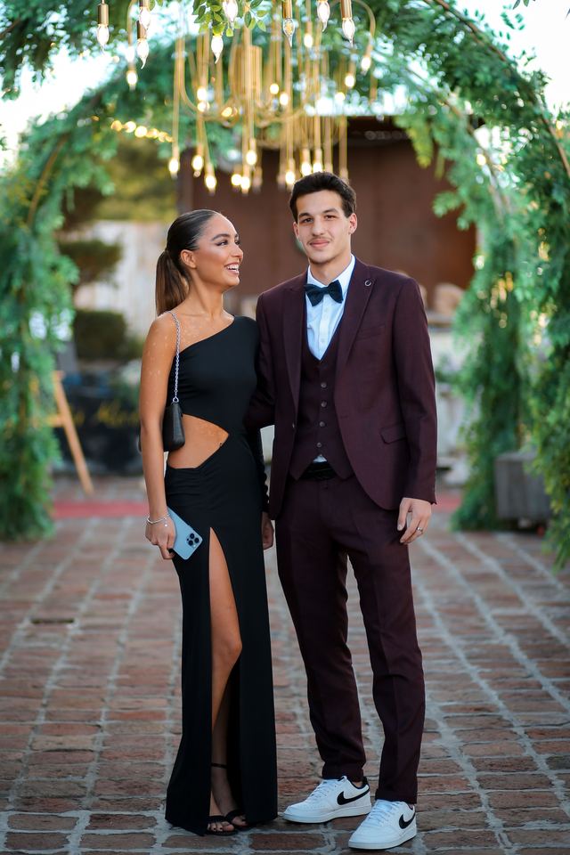Couple dressed for a black tie event under a floral arch